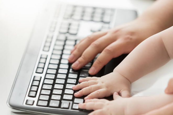 Hände von Erwachsenem und Kind auf einer Tastatur als Symbol für das Urteil familienfreundlicher Betrieb