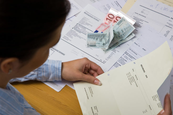 Foto zeigt einen Mann von schräg hinten und vor ihm Papier und Geldscheine bei der Bonitätsprüfung im Unternehmen