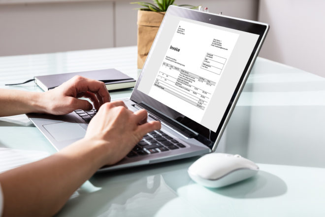 Foto zeigt Hände auf einer Laptoptastatur - auf dem Monitor eine Kleinbetragsrechnung