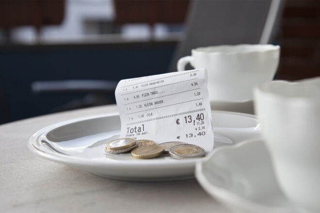 Titelbild Fachbuch Kassenführung in der Gastronomie: Zwei Kaffeetassen und ein Teller, auf dem ein Kassenbon und Münzen liegen.