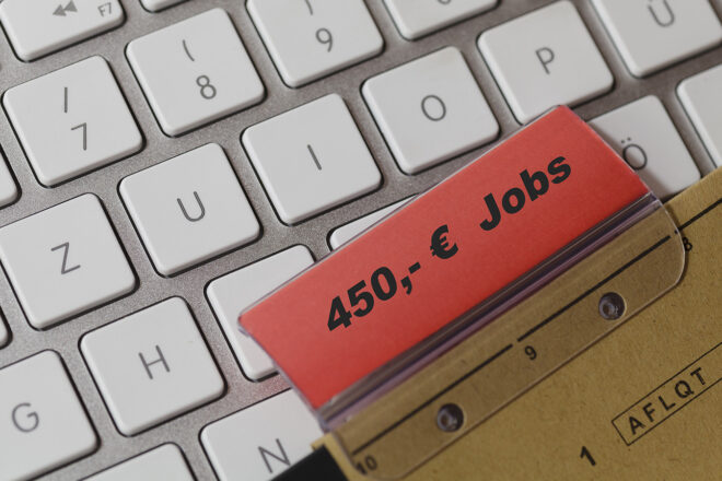 Foto zeigt das Etikett eines Hängeregisters mit der Aufschrift 450-Euro-Jobs schräg auf einer lichtgrauen Tastatur liegend