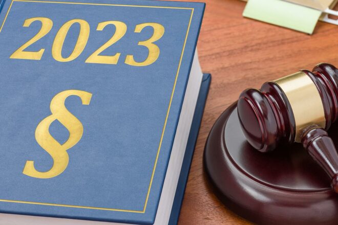 Foto zeigt ein dickes blaues Buch über neue Gesetze 2023 neben einem Richterhammer