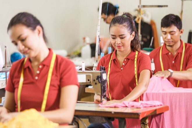 Foto zeigt Beschäftigte in einer Textilfabrik in Asien, die das Lieferkettengesetz schützt.