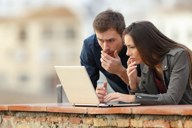 Ein Foto von zwei Menschen am Laptop steht als Symbol dafür, dass es ganz wichtig ist, eine Pishing E-Mail zu erkennen und die Definition und Bedeutung auch durch Beispiele zu verstehen