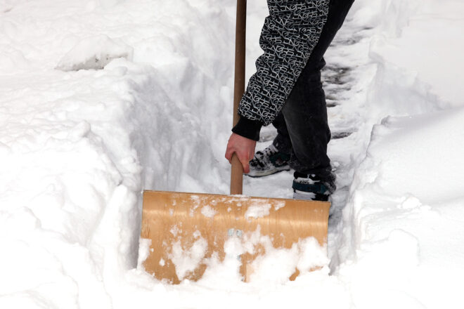 Foto von einem Mann mit Schneeschaufel als Symbol dafr, dass auch Unternehmen im Winter ihrer Räum- und Streupflicht nachkommen müssen.