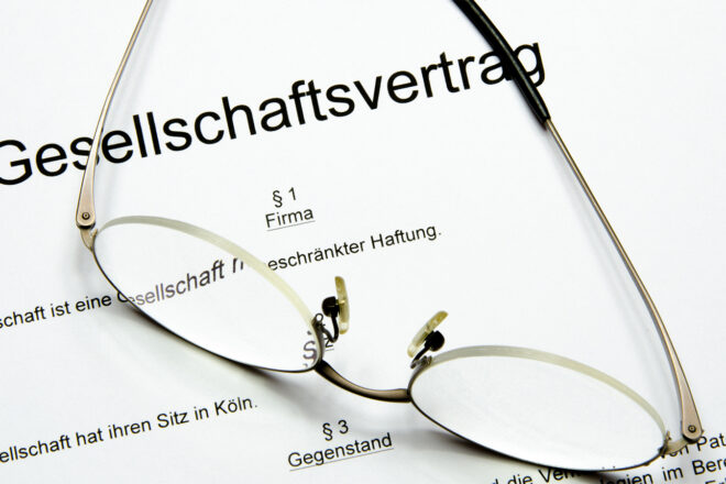 Foto zeigt Brille auf einem Gesellschaftsvertrag, den Unternehmer wegen der Reform der Personengesellschaft gegebenenfalls anpassen sollten