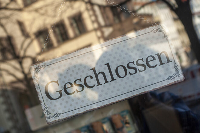 Foto zeigt das GESCHLOSSEN-Schild hinter der sich spiegelnden Scheibe eines Geschäfts in Insolvenz zum Thema Sanierung in Eigenverwaltung
