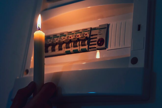 Foto zeigt eine Kerze vor einem Sicherheitskasten zum Thema Schutz vor Stromausfall