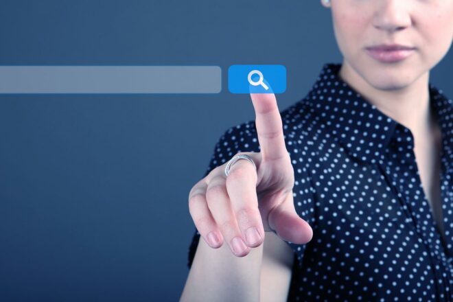 Das Bild einer Fingers auf der Suchlupe einer Website symbolisiert Maßnahmen und KPIs für Search Engine Optimization, kurz SEO