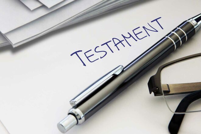 Ein Foto mit einem Papierstück mit der Überschrift Testament, auf dem ein Stift liegt, symbolisiert das Thema Testament.