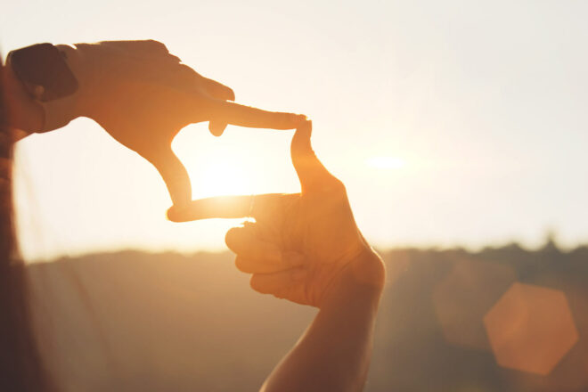 Frauenhände formen ein Rechteck vor dem Sonnenuntergang - Zeit für Unternehmensvisionen