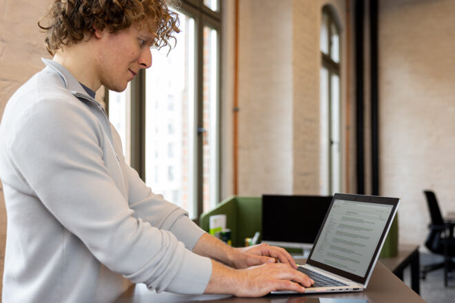 Themenbild DATEV Verlagsmedien Lohn und Personal: Mann steht am Laptop und liest