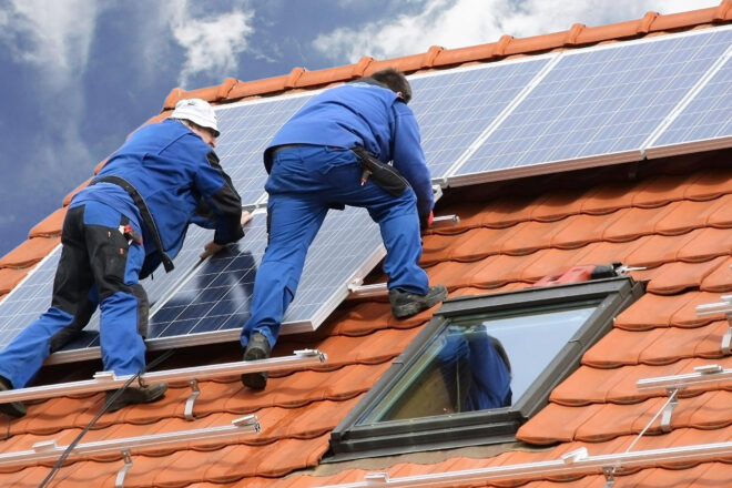 Das Foto zeigt Monteure, die Solarpanels auf einem Hausdach installieren. Für die Lieferung und Montage von Photovoltaikanlagen fällt ab 2023 keine Umsatzsteuer mehr an. Erträge aus dem Stromverkauf sind rückwirkend ab 2022 steuerfrei.