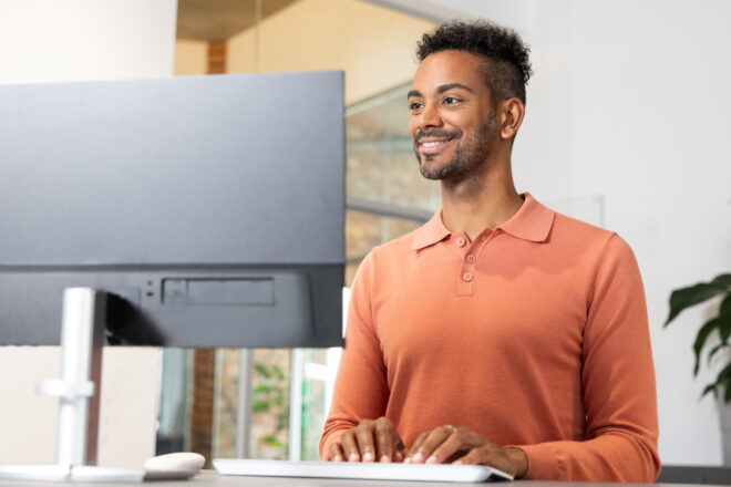 Symbolbild Professionelles Rechnungswesen mit DATEV: Mann steht am Schreibtisch und schaut auf den Monitor.